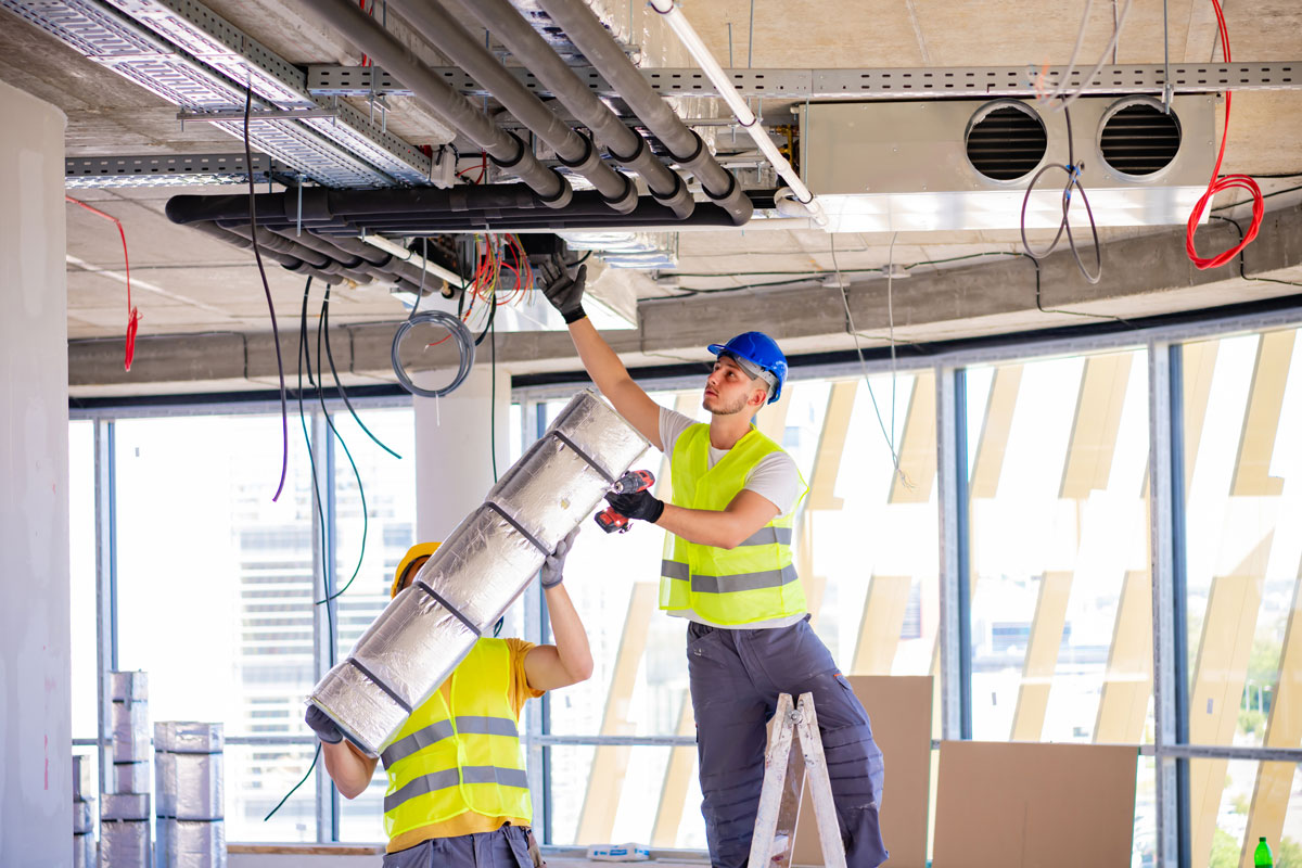 two workers installing HVAC in new construction building